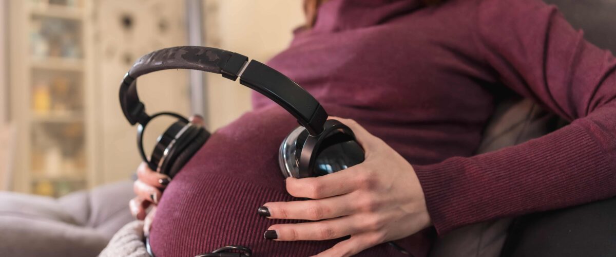 Mujer ubicando audífonos en vientre